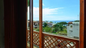 A balcony with a wooden lattice railing, overlooking a residential area with houses and a clear sky. - Villa 'With Pool in Private Park' with Sea View, Wi-Fi and Air Conditioning (Agnone Cilento)
