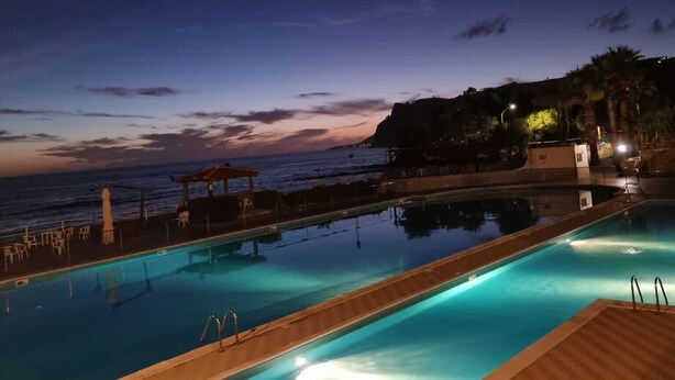 A swimming pool with a view of the ocean at dusk. - Villa 'With Pool in Private Park' with Sea View, Wi-Fi and Air Conditioning (Agnone Cilento)