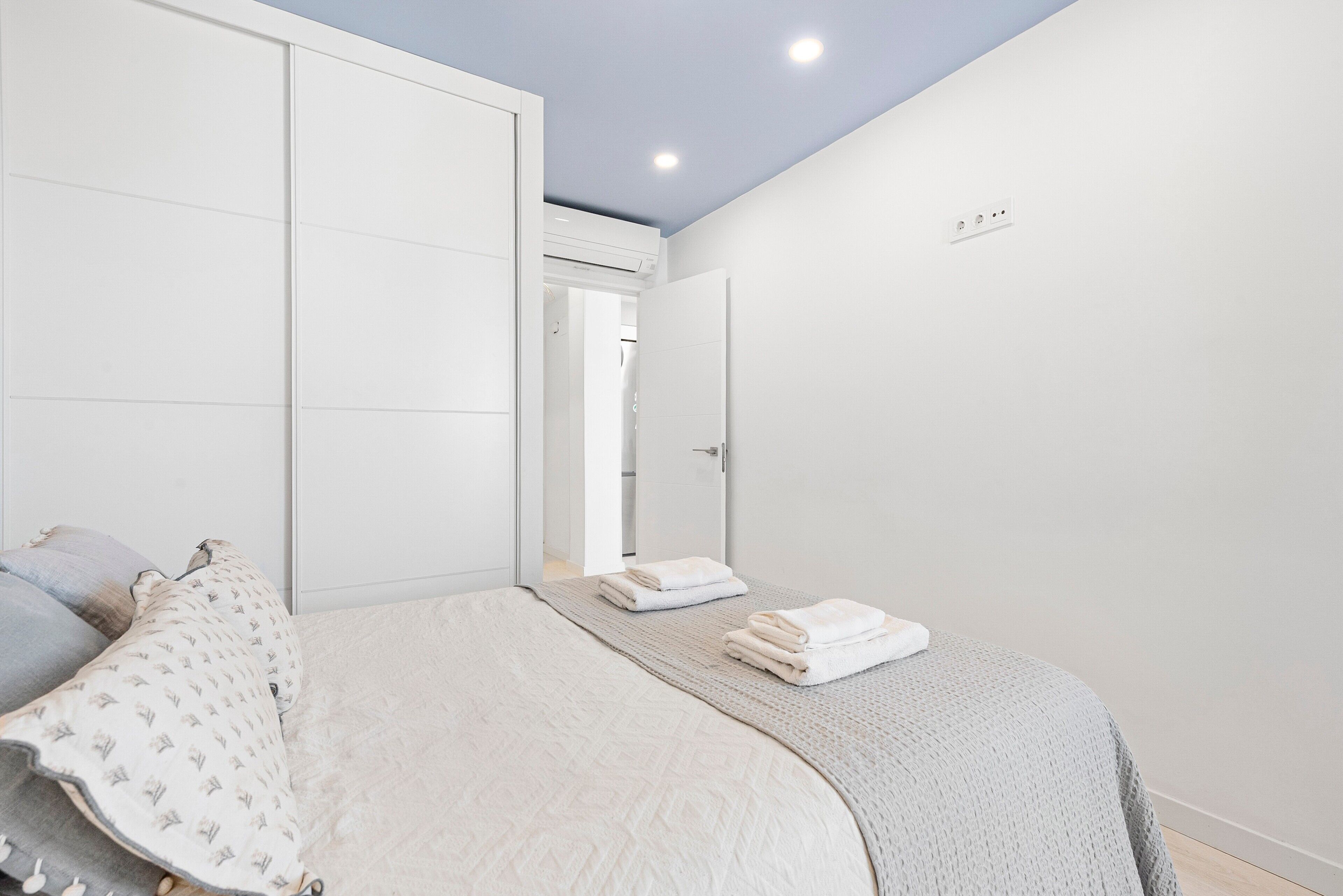 Een slaapkamer met een bed, een garderobe en een deur naar een andere kamer.