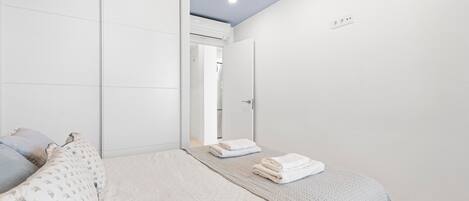 Een slaapkamer met een bed, een garderobe en een deur naar een andere kamer.