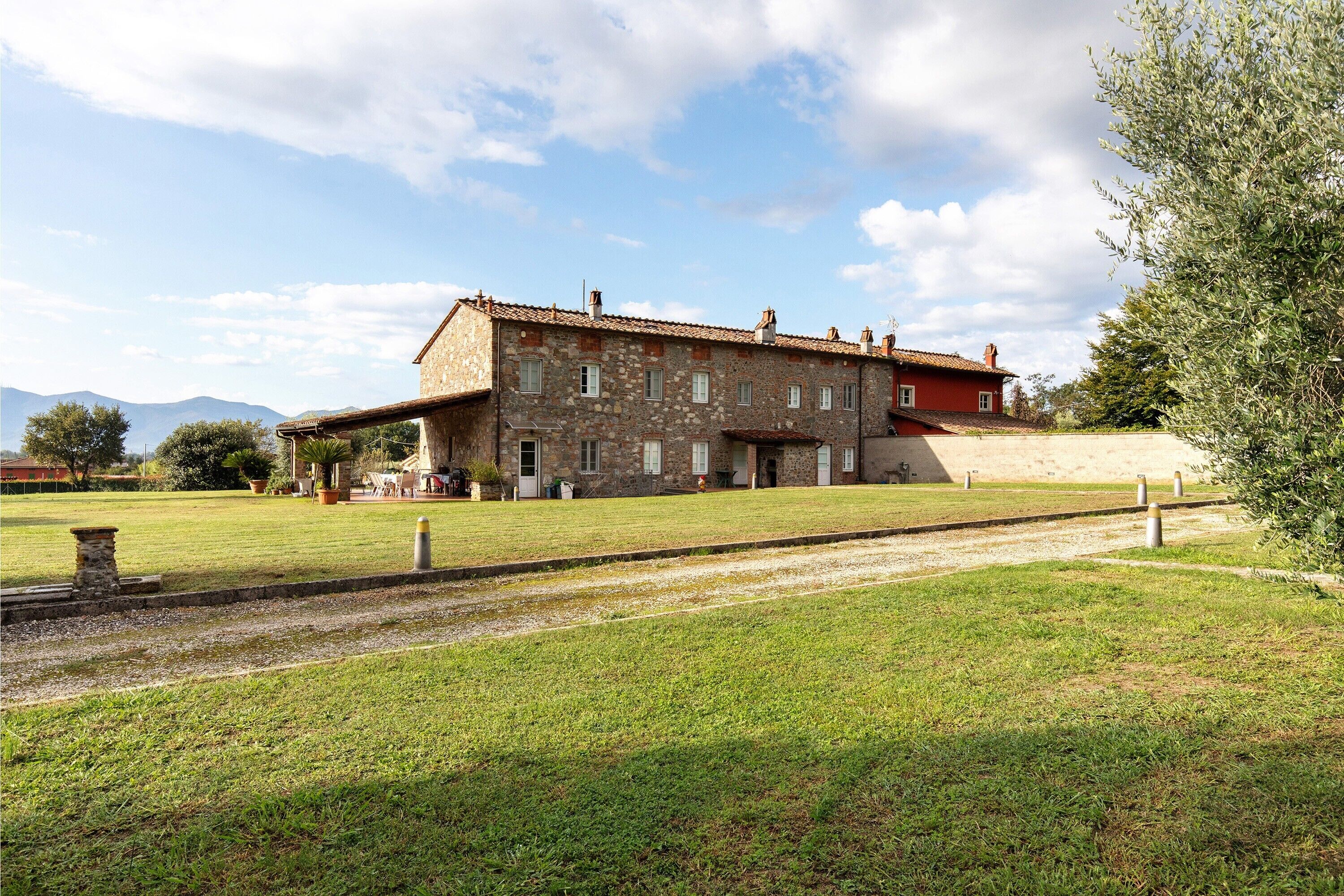 Un bâtiment en pierre avec un toit rouge, une cour verdoyante et un ciel dégagé.