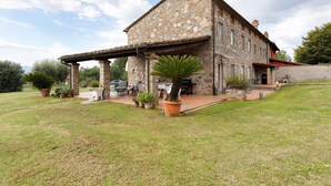 A stone house with a covered patio, outdoor seating, and potted plants. - Villa 'Ringo' with Private Pool, Private Garden and Wi-Fi (Capannori)