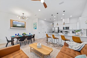 A modern kitchen with white cabinets, a central island, and pendant lighting. - The Palms at Vincente (Panama City Beach)