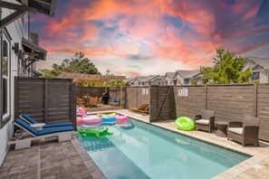 A backyard with a swimming pool, inflatable toys, and outdoor furniture.