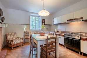 Una cocina con mesa, sillas, estufa y una lámpara colgante.