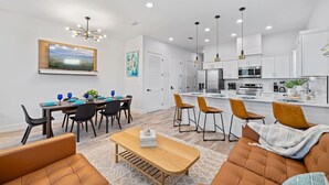 A modern kitchen with white cabinets, a central island, and pendant lighting. - 5BDR~Heated Pool+Golf Cart+Grill+Pool Table (Panama City Beach)