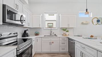 Een moderne keuken met witte kastjes, roestvrijstalen apparatuur en een centraal kookeiland.