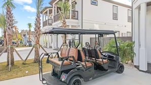 Un golf cart parcheggiato in un vialetto, con un edificio residenziale sullo sfondo.