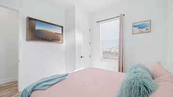 Ein Schlafzimmer mit Bett, Fenster mit Jalousien, einer Tür und einem Deckenventilator.