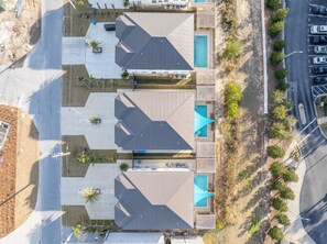 Um hotel com vários andares, piscina no terraço, área de estar ao ar livre e estacionamento.