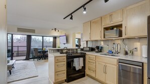 A modern kitchen with wooden cabinets, a built-in oven, a microwave, and a dishwasher. - Downtown City Walk High-Rise 2BR | GYM | Sauna (Colorado Springs)