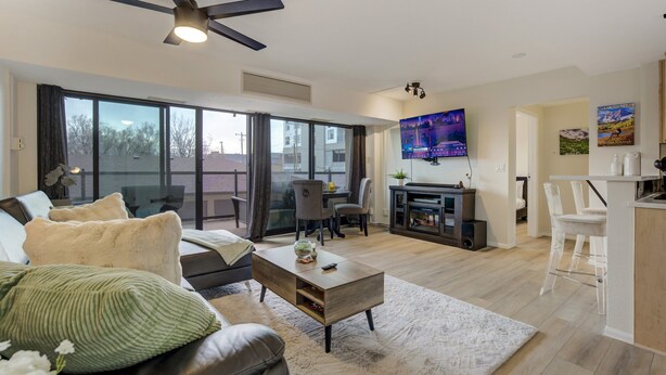 A modern living room with a sofa, coffee table, and a TV mounted on the wall. - Downtown City Walk High-Rise 2BR | GYM | Sauna (Colorado Springs)