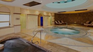 Un espace spa comprenant un jacuzzi, des chaises longues et un sol carrelé en pierre.