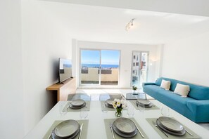 A dining area with a table set for six, a sofa, and a view of the sea.