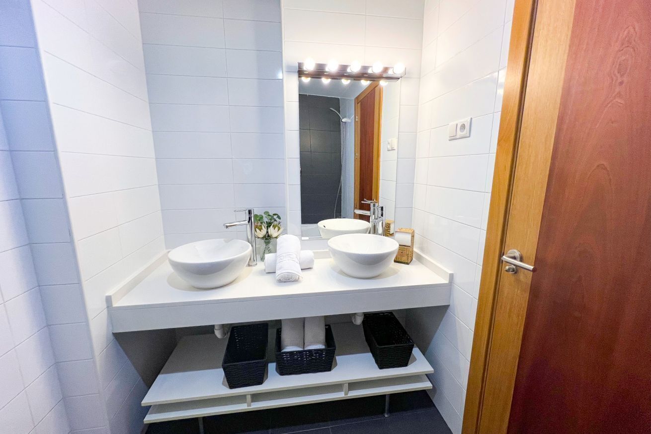 Un baño moderno con dos lavamanos, un espejo con iluminación y una ducha.