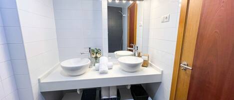 Un baño moderno con dos lavamanos, un espejo con iluminación y una ducha.