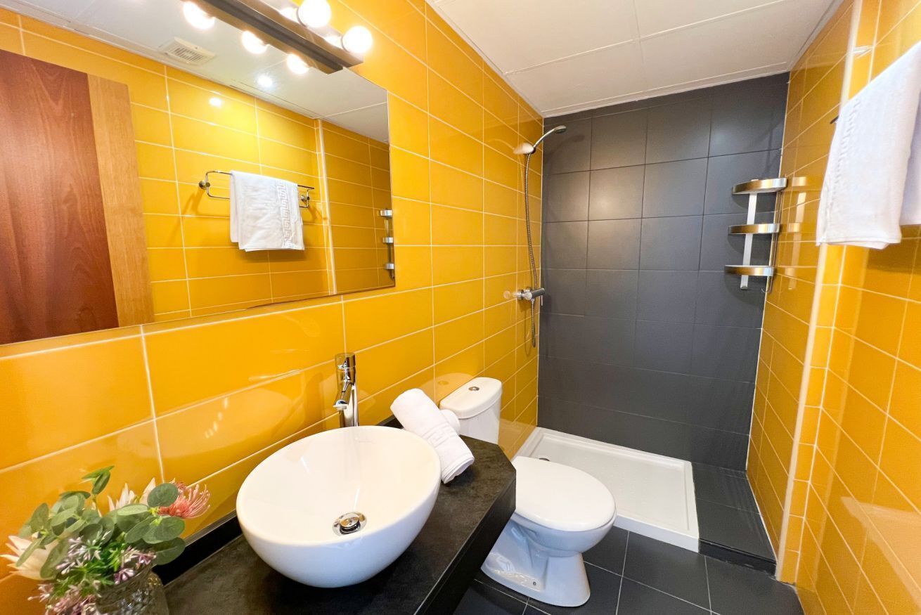 Et badeværelse med stor vask, toilet og brusebad.