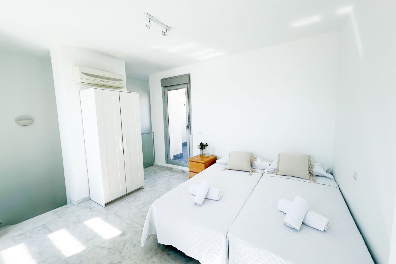 A hotel room with a bed, a wardrobe, a nightstand, and a door leading to a balcony.