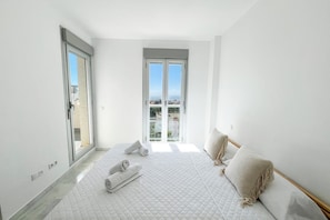 A bedroom with a large bed, a sliding glass door, and a view of the city.