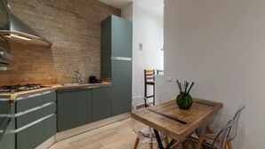 Una cocina moderna con pared de ladrillo, electrodomésticos de acero inoxidable y una mesa de comedor de madera.