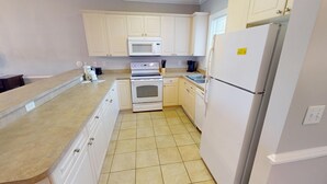 A kitchen with white cabinets, a microwave, an oven, a refrigerator, and a sink.