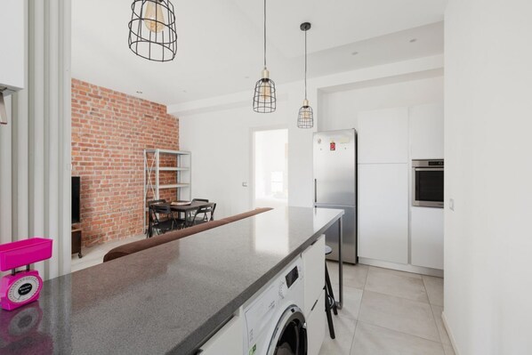 A modern kitchen with a brick wall, stainless steel appliances, and pendant lighting.