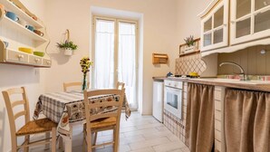 Cucina con tavolo da pranzo, sedie, pensili e una finestra.