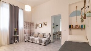 Una camera da letto con un letto, un divano, un tavolino con un vaso e un'area pranzo sullo sfondo.