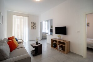 A modern living room with a sofa, a coffee table, a TV, and a bookshelf.