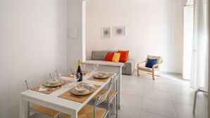 A dining area with a table set for four, a sofa with colorful cushions, and a chair with a blue cushion. - GuestHost - A Step from the Beach - Roomy Apt with Sea Glimpse (Arma di Taggia)