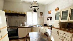 Una cocina compacta con mesa de comedor, lámpara colgante y salpicadero de azulejos.