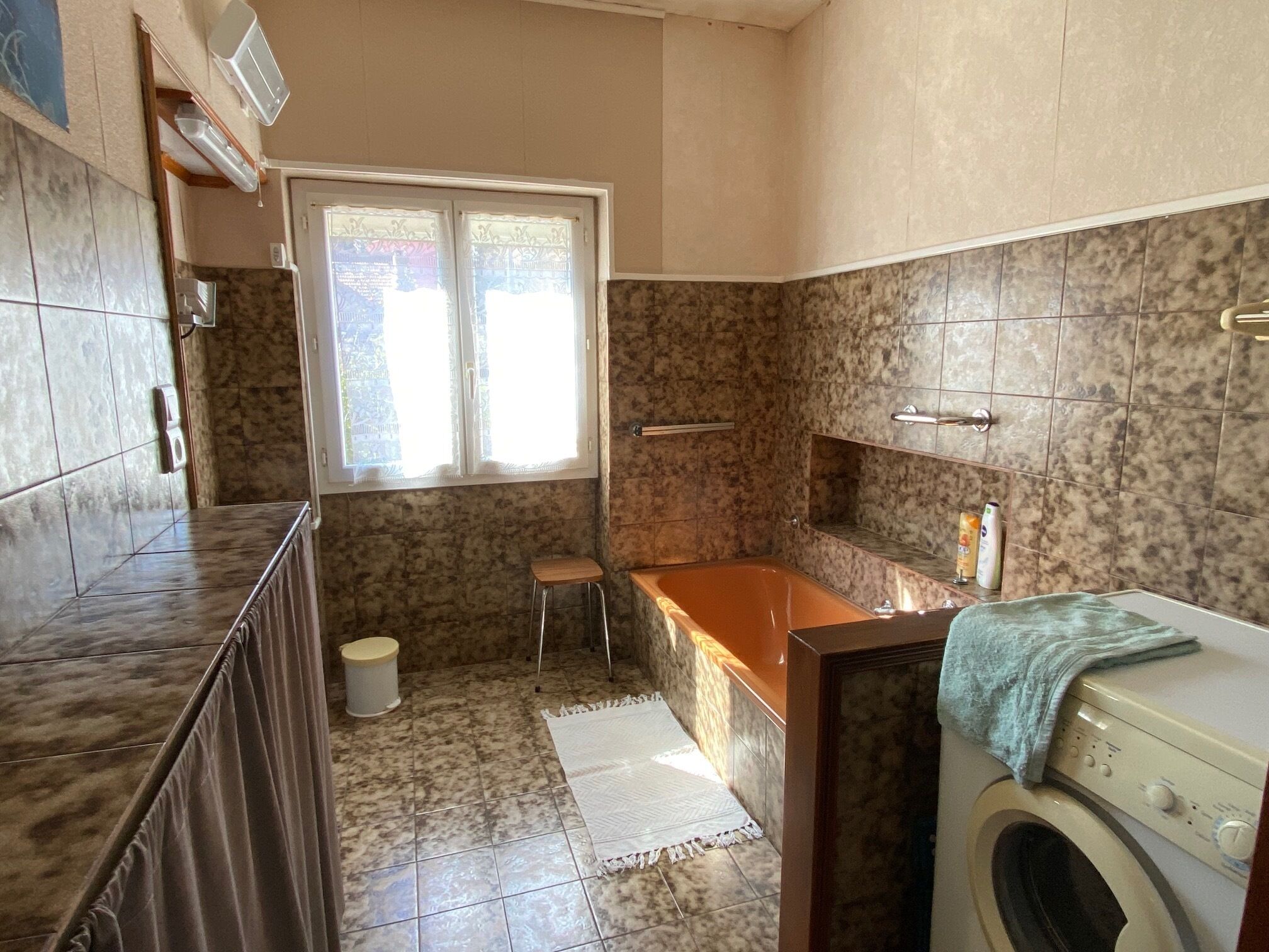 Een badkamer met een wasmachine, een badkuip en een toilet.