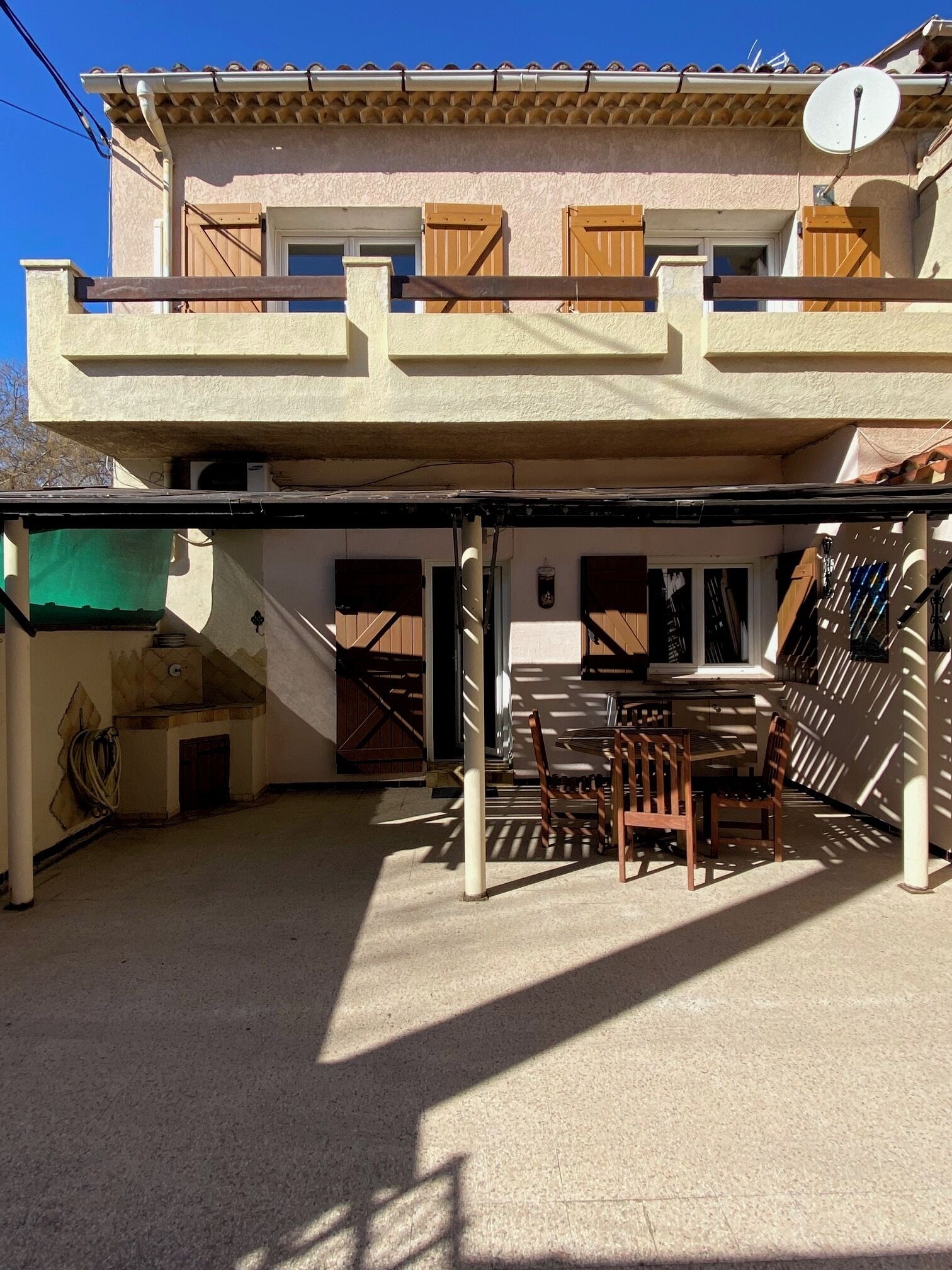 A two-story building with a covered patio area featuring a table and chairs.