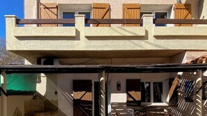 Un edificio de dos pisos con un patio cubierto que incluye una mesa y sillas.