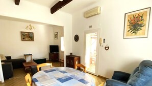 Una sala de estar con una mesa de comedor, un sofá azul y una televisión.