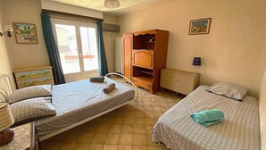 Una habitación con dos camas, un armario, un radiador y una ventana con cortinas.