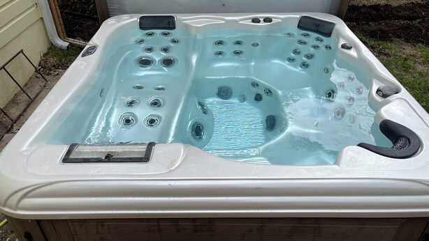 Un jacuzzi con múltiples chorros, un panel de control y un pasamanos de seguridad.
