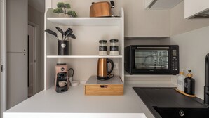 Une cuisine compacte équipée d’un four à micro-ondes, d’une machine à café et d’étagères de rangement.