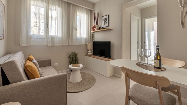 Un salon moderne comprenant un canapé, un téléviseur, une table à manger et une petite table d’appoint sur laquelle est posée une plante.