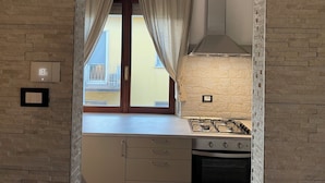 Eine Küche mit Gasherd, einer modernen Dunstabzugshaube und einem Fenster mit Vorhängen.