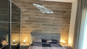 Ein modernes Schlafzimmer mit einem Holz-Kopfteil, einem gro ßen Spiegel und einer Bettdecke mit Karomuster.