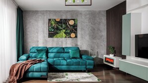 A modern living room with a teal sofa, a fireplace, and a large TV.