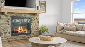 A cozy living room with a stone fireplace, a comfortable sofa, and a round coffee table.