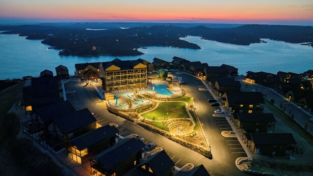 A resort with a swimming pool, multiple buildings, and a view of the surrounding water.