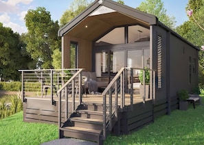 A modern, single-story cabin with a covered porch, a staircase, and a seating area.