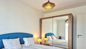 Une chambre à coucher avec un grand lit, une armoire en bois, un miroir et deux lampes de chevet.
