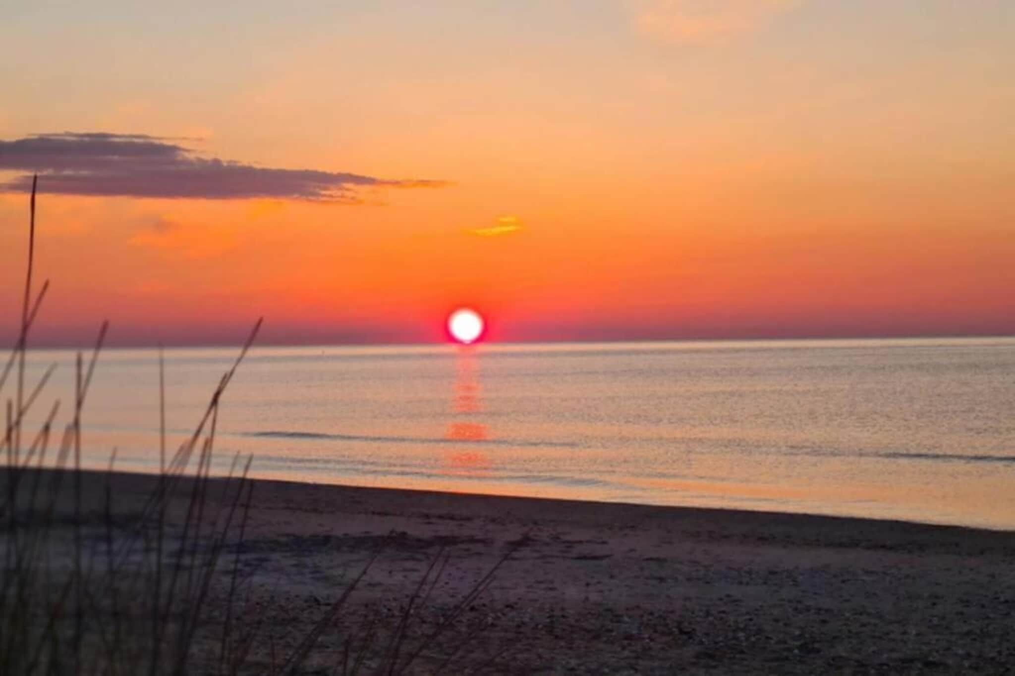 Un capvespre sobre una platja amb mar tranquil i un horitzó clar.