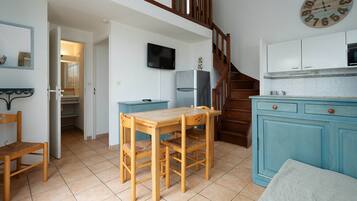 Eine Küche mit einem Holztisch, Stühlen, einem blauen Schrank und einer Uhr an der Wand.