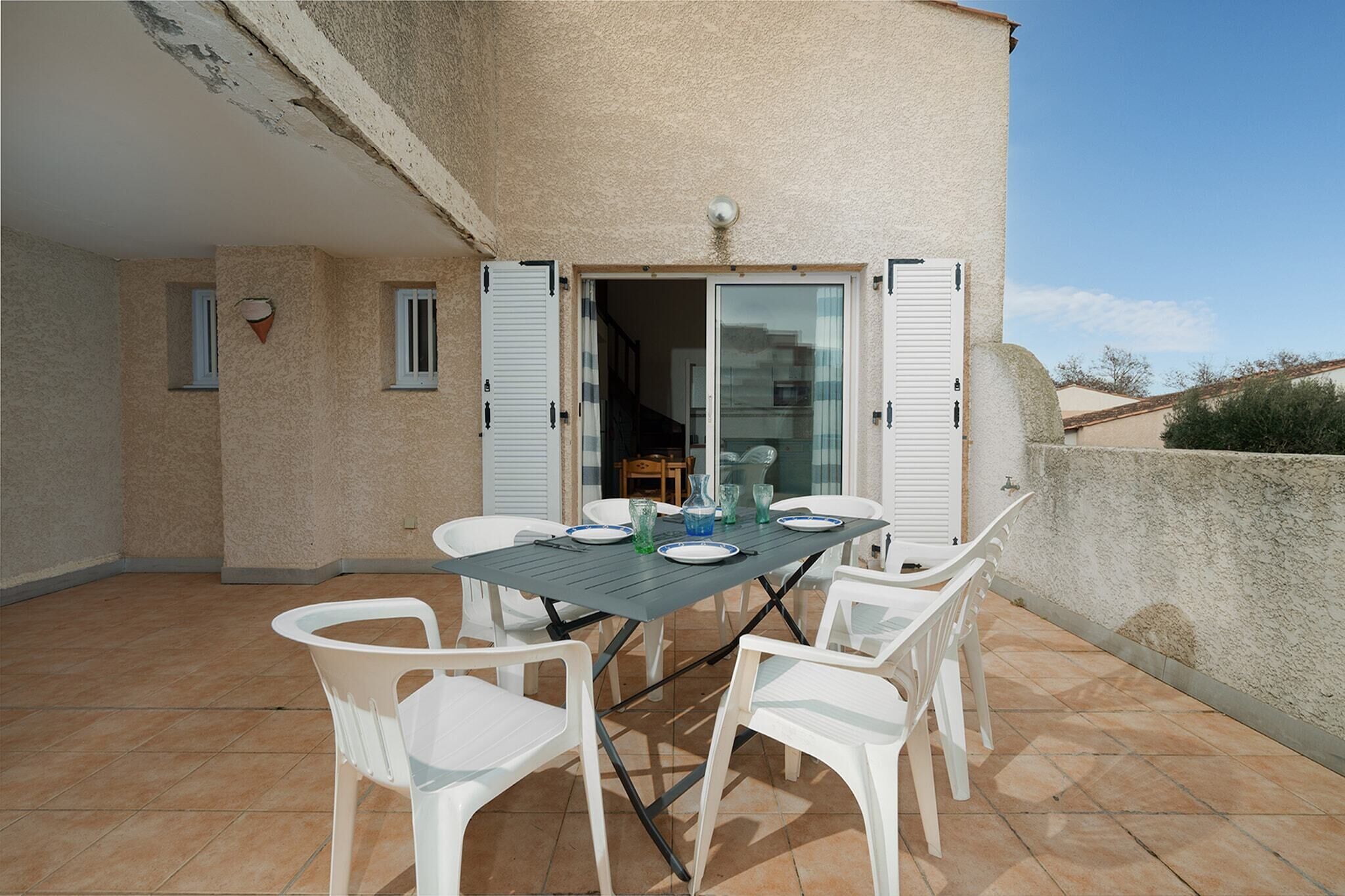 A patio with a table and chairs, a sliding glass door, and a view of the interior.