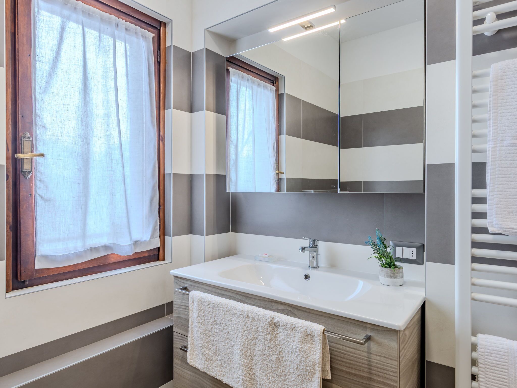 Une salle de bain moderne avec un grand miroir, un lavabo et un porte-serviettes.